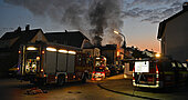 Brennendes Wohnhaus mit Rauchwolken und Löscharbeiten im Morgengrauen